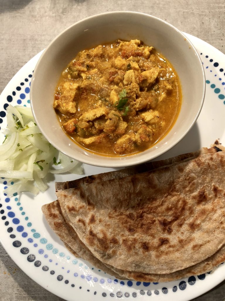 Chicken curry served with sliced onions and rotis