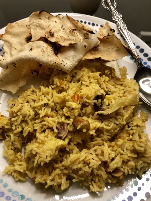 Tomato Rice with papad on a white plate