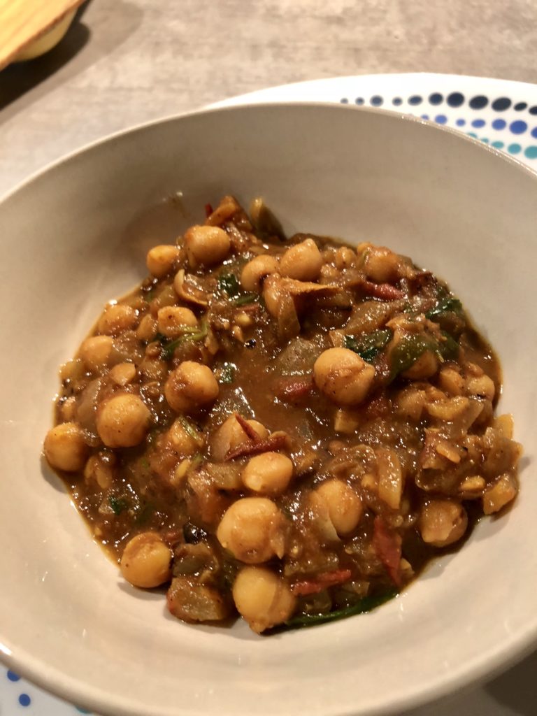 Chlole or chickpeas curry in a tomatoey curry served in a white bowl alongside roti