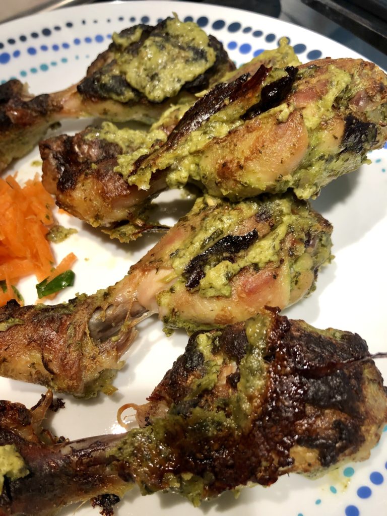 Crispy browned green chicken drumsticks on a white pate