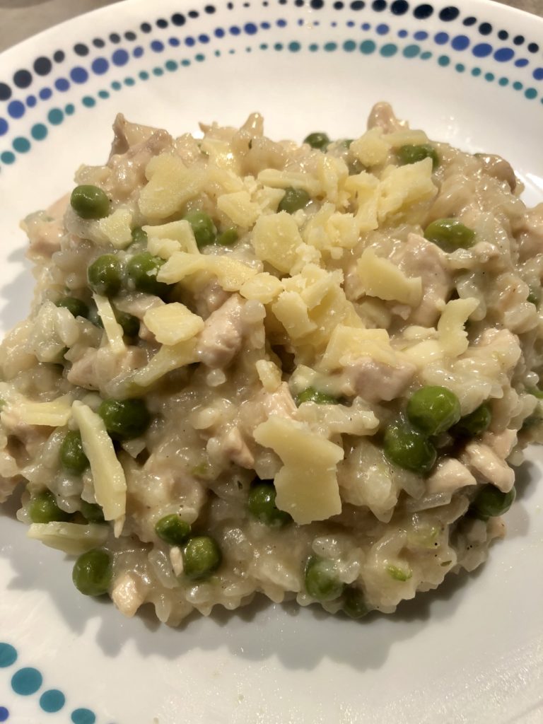 Chicken and peas risotto served on a white plate with blue and green design
