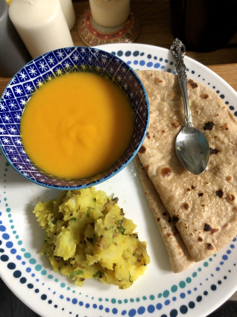 Picnic potatoes with aam was ( mango puree) and rotis on a white plate