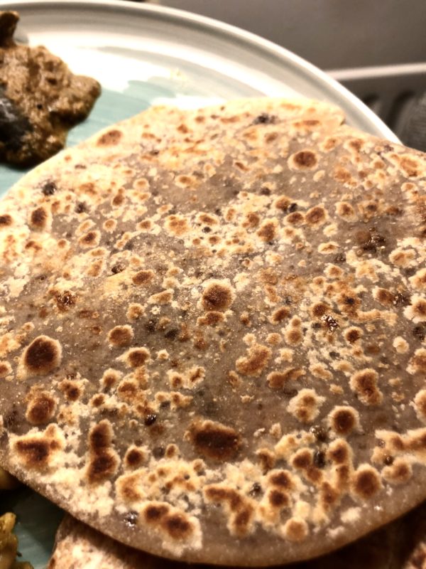 Flatbread with jaggery and sesame seeds on a white dish
