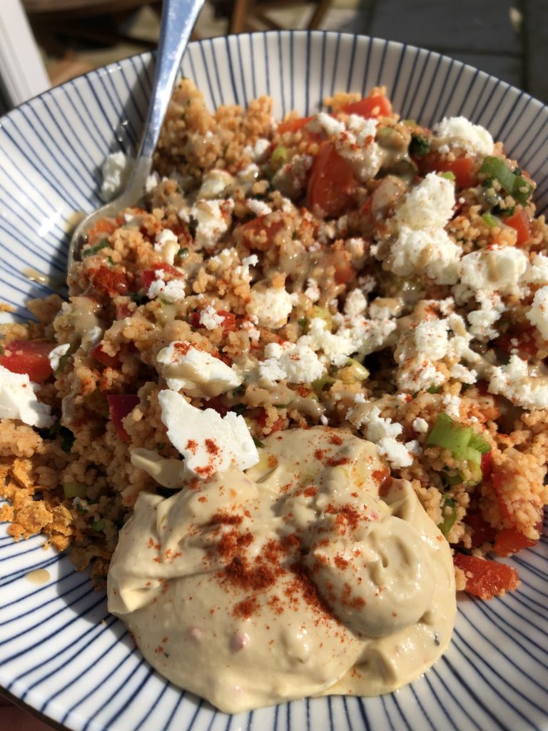 Bowl with couscous sprinkled with paprika and feta served alongside feta cheese