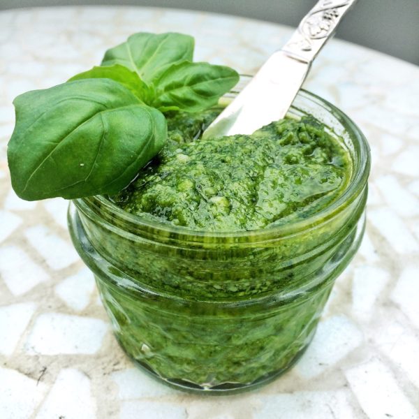 Pesto made with basil, pine nuts , Parmesan cheese, garlic and olive olive in a glass jar topped with basil leaves