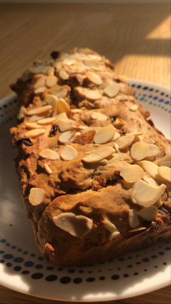 Sugarfree banana bread topped with flaked almonds on a white dish