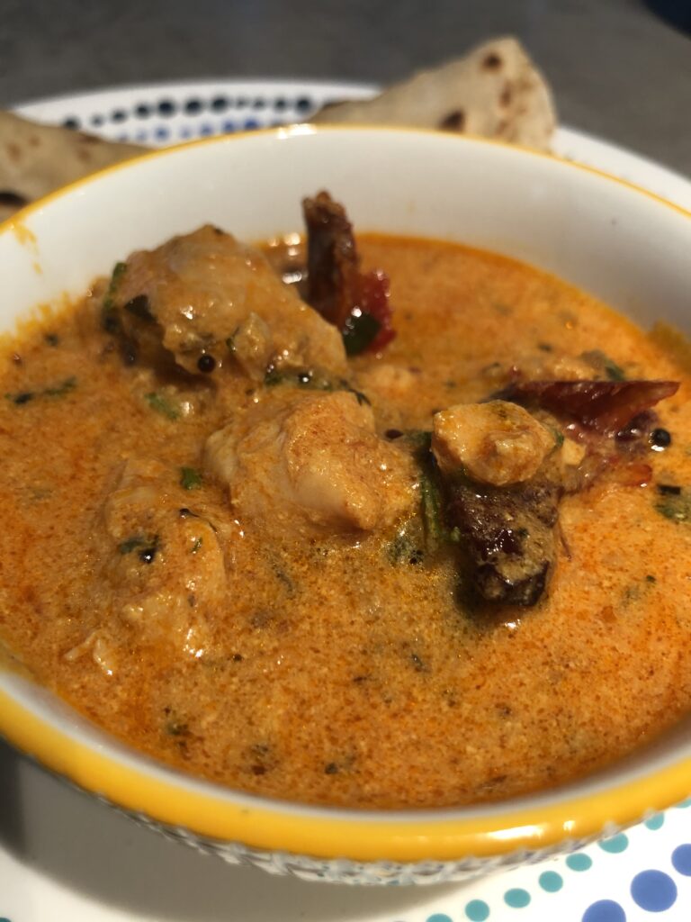 Achari chicken curry - a chicken curry in pickling spice served in a white bowl alongside rotis